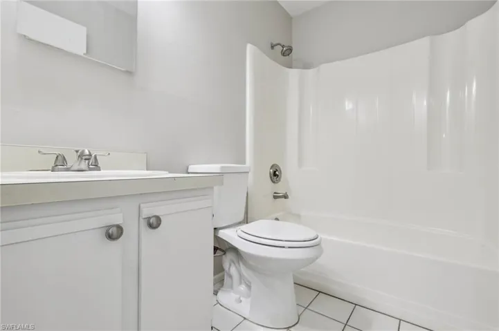 Bathroom featuring light tile patterned flooring, vanity, and washtub / shower combination