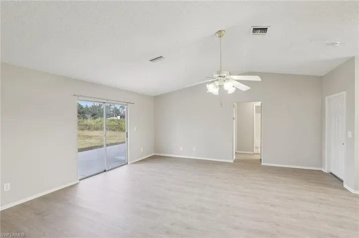Unfurnished room featuring light wood finished floors, vaulted ceiling, a textured ceiling, and a ceiling fan