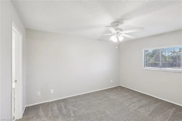 Unfurnished room featuring carpet floors, a textured ceiling, and ceiling fan