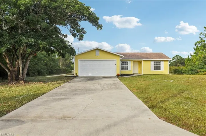 View of front of property featuring driveway, a front yard, and an attached garage