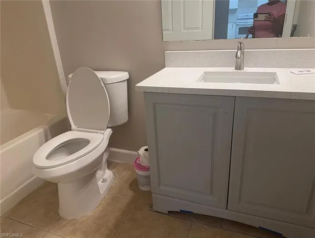 Bathroom featuring a white vanity with paneling, a light-colored speckled countertop, an integrated rectangular sink, and a brushed nickel faucet