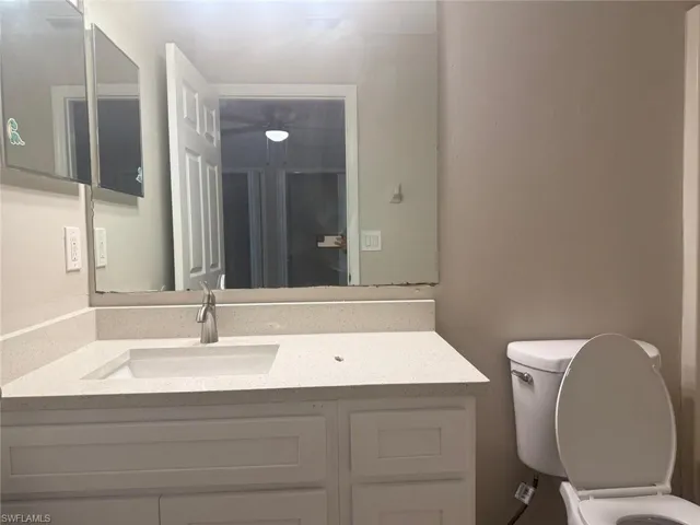 Bathroom vanity featuring white cabinetry, an integrated sink, a speckled countertop, and a single-handle faucet