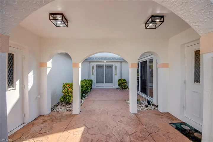 Garage door on left-kitchen hall door on right.  Walkway is under roof.  Double door entry.