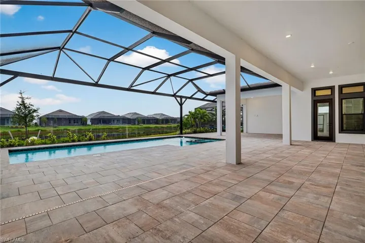 Outdoor pool with a patio area, a sunroom, glass enclosure, and a residential view