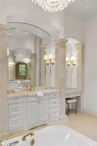Bathroom with ornamental molding, ornate columns, vanity, and a bathing tub