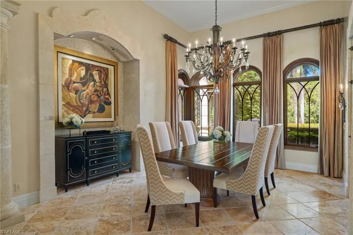 Tiled dining area with decorative columns, a chandelier, and ornamental molding