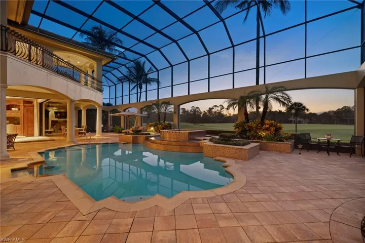 Pool at dusk featuring a patio and an in ground hot tub