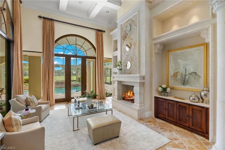 Living room featuring beam ceiling, light tile patterned flooring, crown molding, coffered ceiling, and a high end fireplace