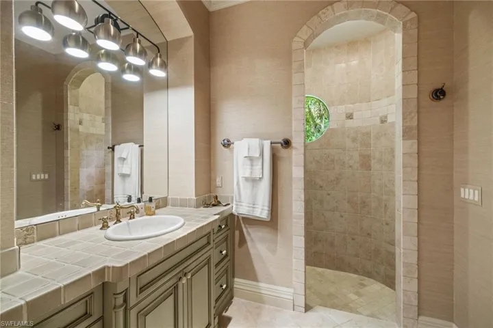 Bathroom featuring vanity, tile patterned floors, and a tile shower