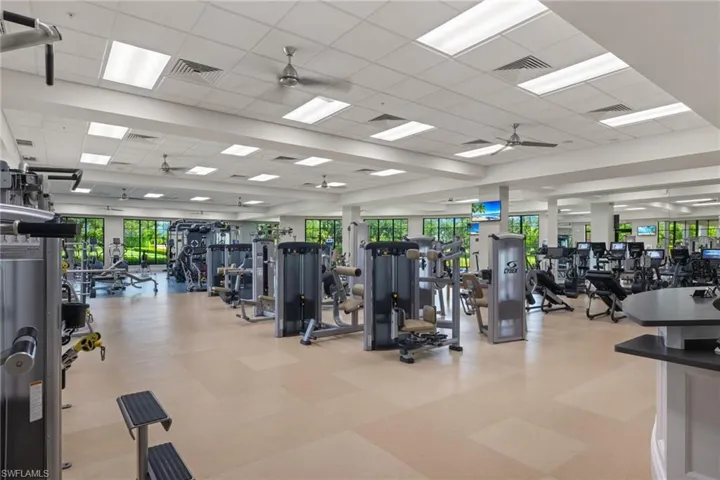 Gym with a healthy amount of sunlight, ceiling fan, and a paneled ceiling