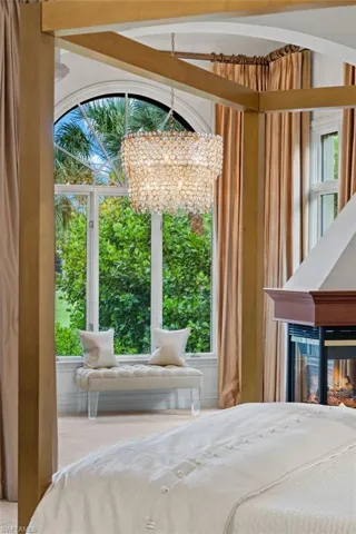 Bedroom featuring carpet, a chandelier, a multi sided fireplace, and lofted ceiling