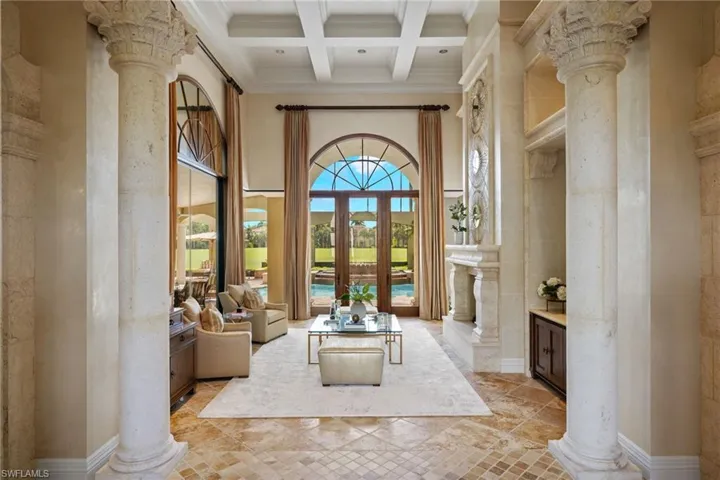 living room w/ fireplace and featuring beam ceiling, light tile patterned flooring, decorative columns, coffered ceiling, and a towering ceiling