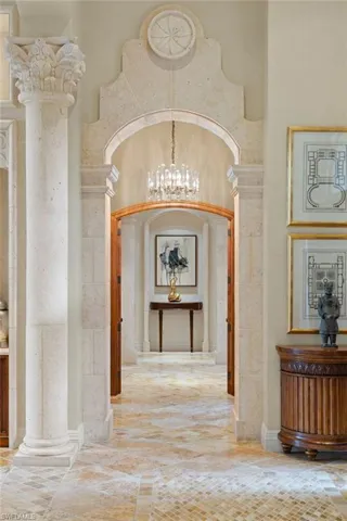 Hall with tile patterned floors, decorative columns, and a chandelier