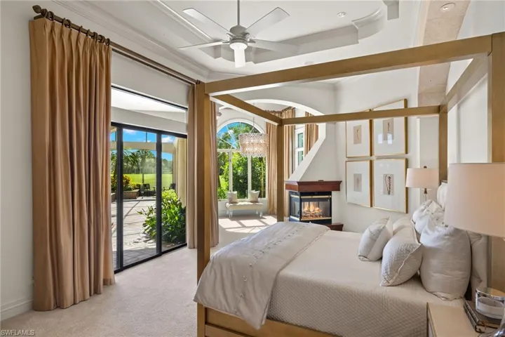 Carpeted bedroom featuring ceiling fan, access to outside, a multi sided fireplace, and ornamental molding