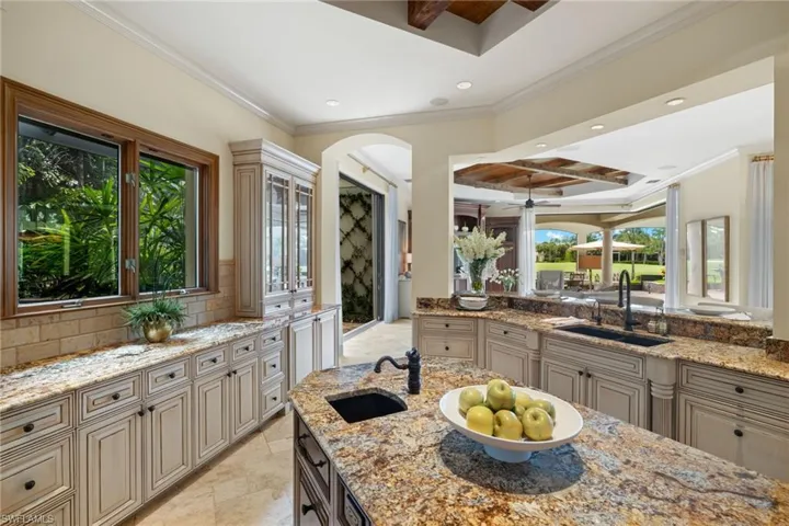 Kitchen with sink, light stone counters, a healthy amount of sunlight, and light tile patterned floors