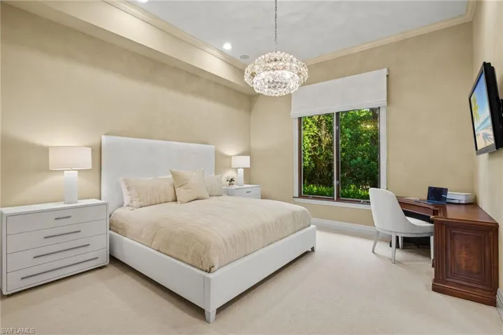 Bedroom featuring a notable chandelier, ornamental molding, and light colored carpet