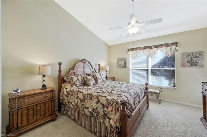 Bedroom with light colored carpet, a ceiling fan, and lofted ceiling