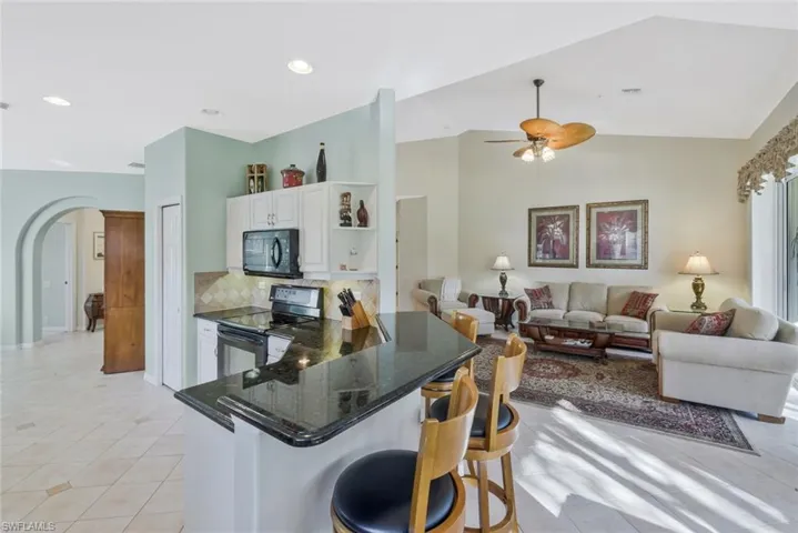 Kitchen with arched walkways, open floor plan, stainless steel electric stove, light tile patterned floors, and lofted ceiling