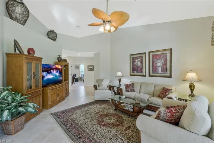 Living room featuring light tile patterned floors, a high ceiling, and a ceiling fan