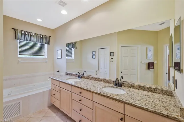 Full bath with a bath, double vanity, light tile patterned floors, and recessed lighting