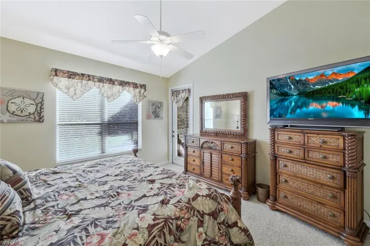 Bedroom with light colored carpet, vaulted ceiling, and a ceiling fan