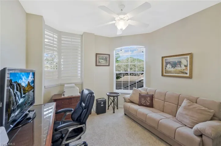 Carpeted home office featuring ceiling fan and baseboards
