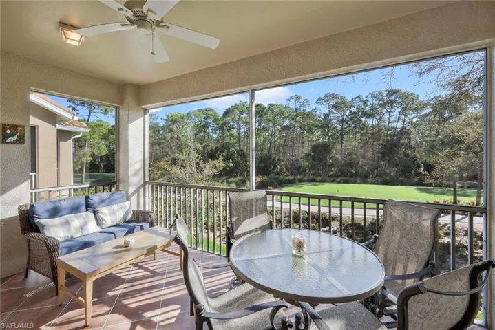 Sunroom featuring a balcony, ceiling fan, an outdoor living / dining area, and view of scattered trees