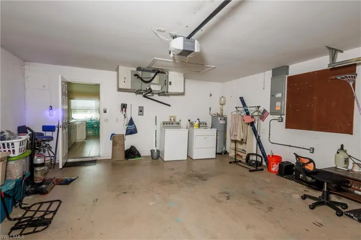 Garage featuring washer and dryer, electric water heater, a garage door opener, and electric panel