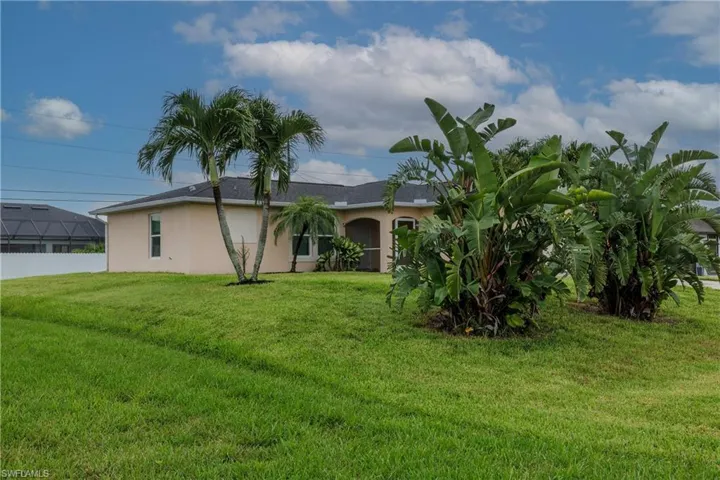 Back of house with stucco siding and a yard