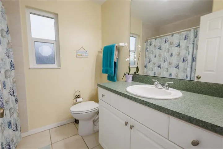 Full bath featuring tile patterned flooring, vanity, and a shower with shower curtain