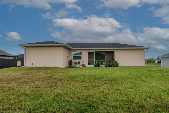 Rear view of property featuring stucco siding and a lawn
