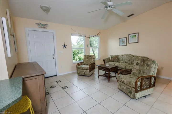 Living area with a ceiling fan, light tile patterned flooring, and lofted ceiling