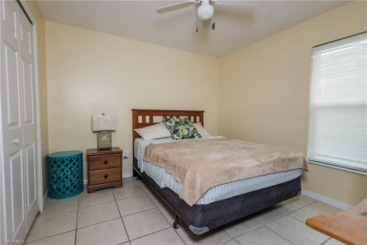 Bedroom featuring a closet, light tile patterned flooring, and ceiling fan
