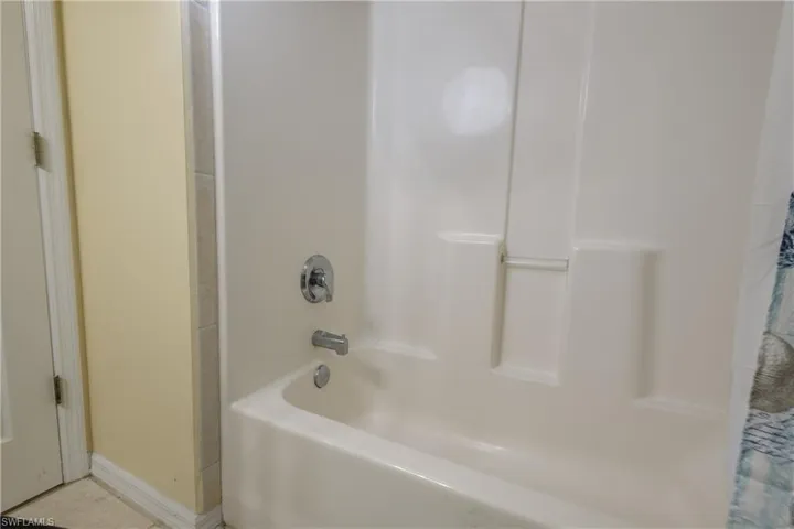 Bathroom featuring shower / tub combo and baseboards