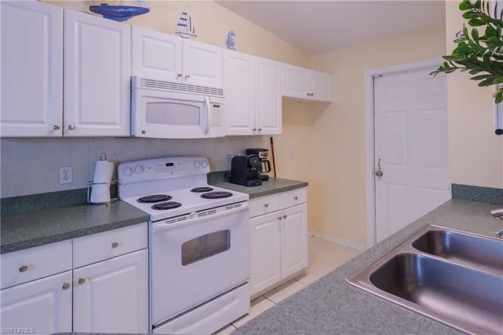 Kitchen featuring white appliances, white cabinets, and light tile patterned flooring
