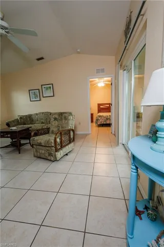 Living room featuring vaulted ceiling, ceiling fan, and light tile patterned floors