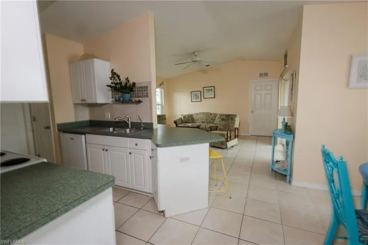 Kitchen featuring open floor plan, a ceiling fan, a peninsula, lofted ceiling, and light tile patterned floors