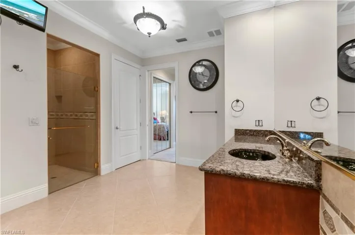 Bathroom with vanity, ornamental molding, tile patterned floors, and tiled shower