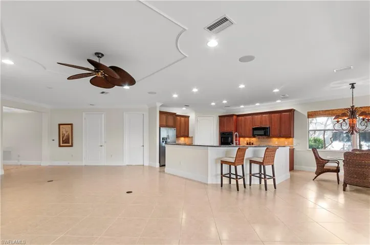 Kitchen with black appliances, ornamental molding, decorative backsplash, and a kitchen breakfast bar