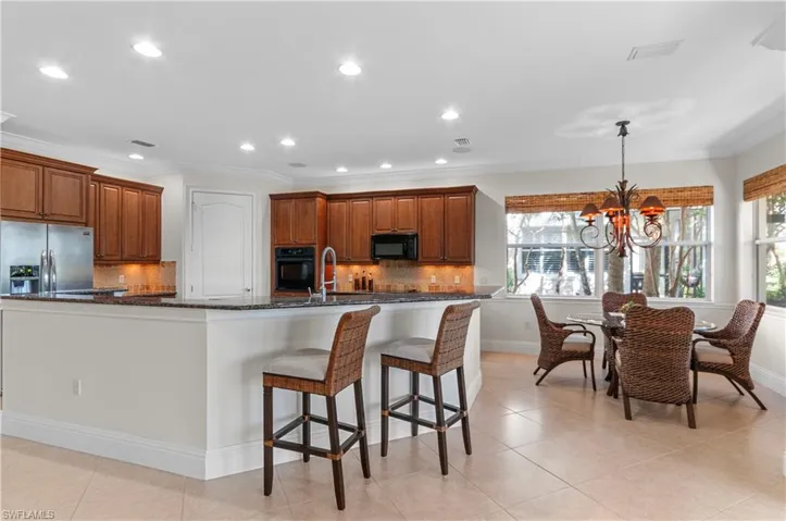 Kitchen with black appliances, hanging light fixtures, dark stone counters, decorative backsplash, and a chandelier