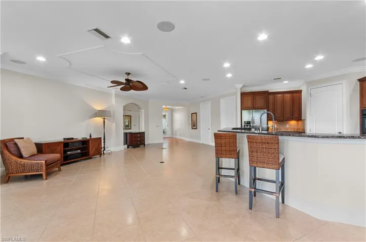 Kitchen featuring tasteful backsplash, kitchen peninsula, ceiling fan, crown molding, and a breakfast bar