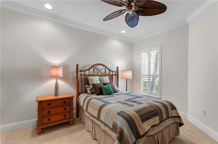 Carpeted bedroom featuring crown molding and ceiling fan