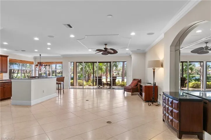 Living room featuring ornamental molding, ceiling fan with notable chandelier, and light tile patterned floors