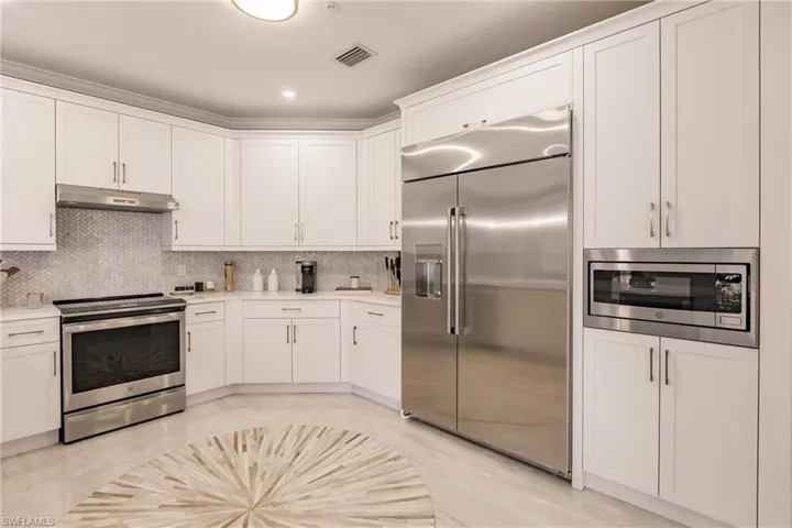 Kitchen with built in appliances, decorative backsplash, and white cabinets