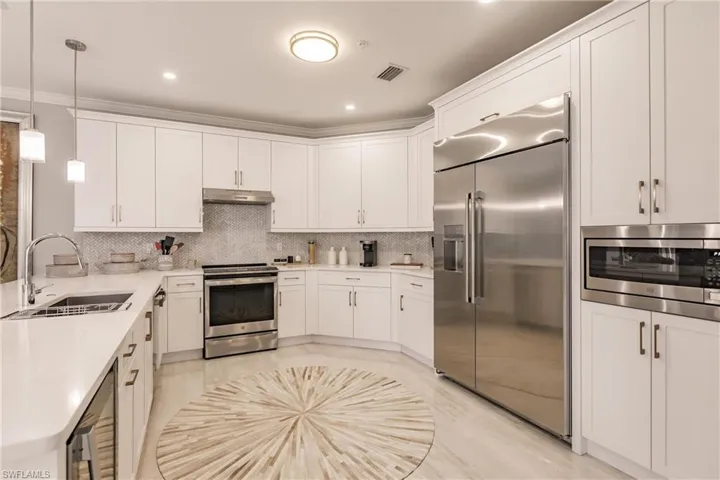 Kitchen featuring built in appliances, pendant lighting, crown molding, sink, and decorative backsplash
