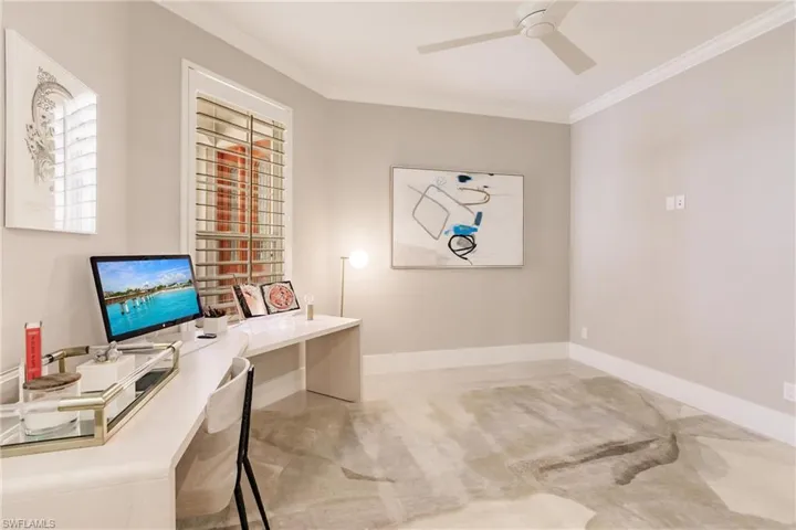 Home office with crown molding, ceiling fan, and light carpet