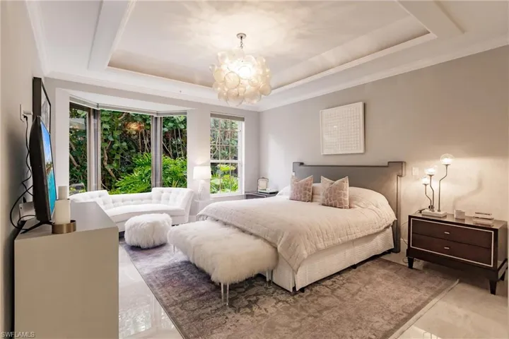 Bedroom with crown molding, a chandelier, and a tray ceiling