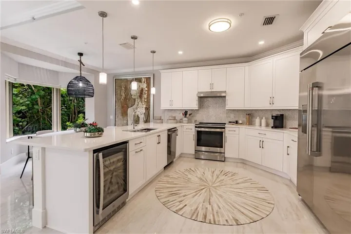 Kitchen with wine cooler, pendant lighting, stainless steel appliances, sink, and white cabinets