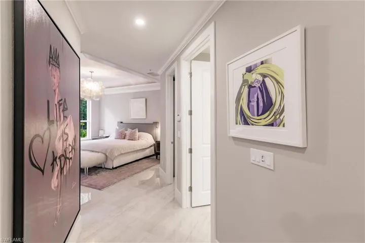 Hallway with crown molding and an inviting chandelier