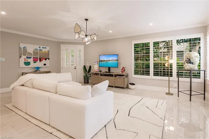 Living room featuring a notable chandelier and ornamental molding